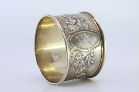 Argola de guardanapo em prata com motivos florais relevados envolvendo cartela para monograma.